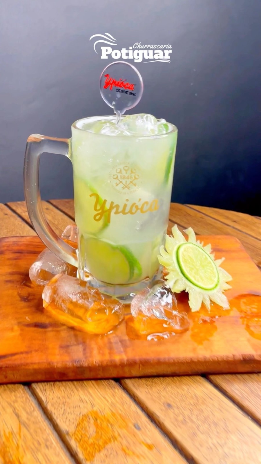 Caneca de caipirinha com gelo e limão sobre tábua de madeira, fotografia do perfil oficial
